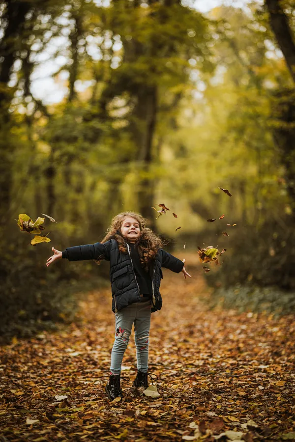 Maedchen wirft Herbstlaub in die Luft - Herbstshooting Berlin