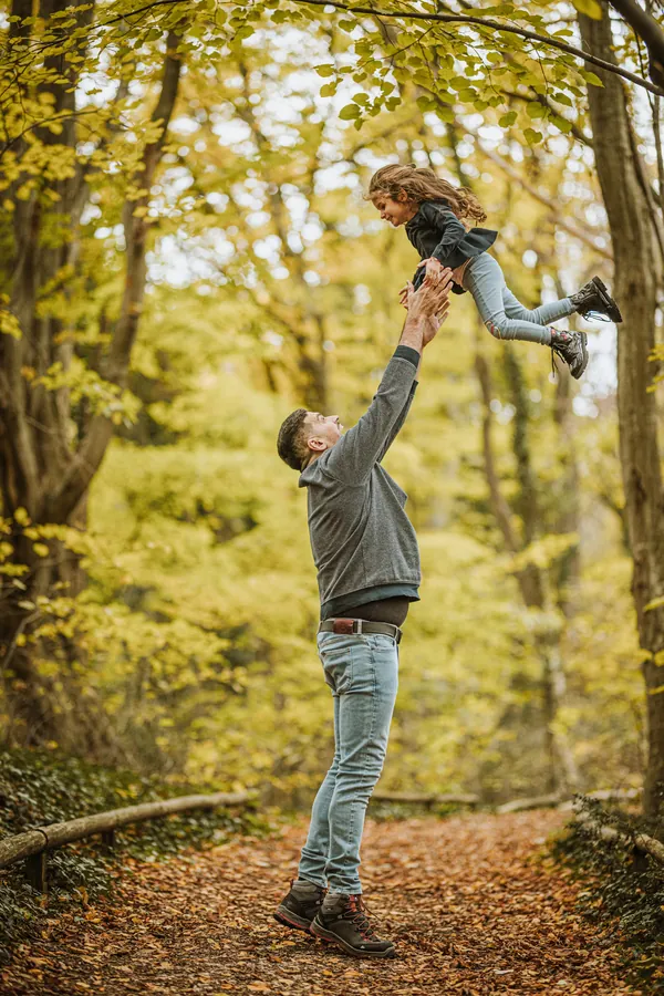 Vater wirft seine Tochter in die Luft im Herbstwald
