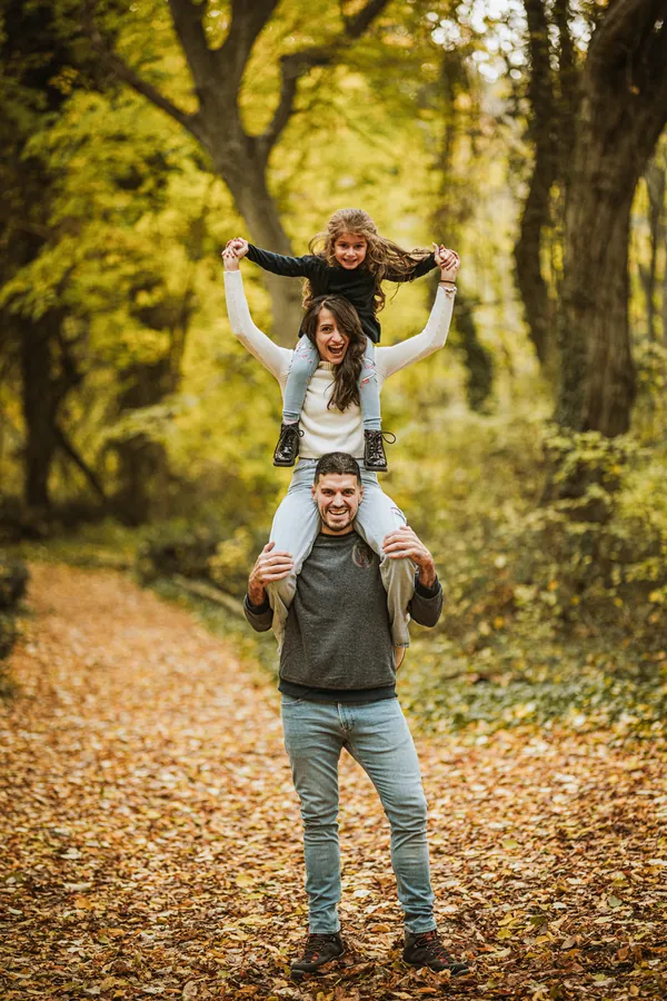 Kind auf den Schultern des Vaters im Herbstwald